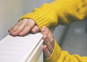 Une femme se chauffe les mains sur un radiateur