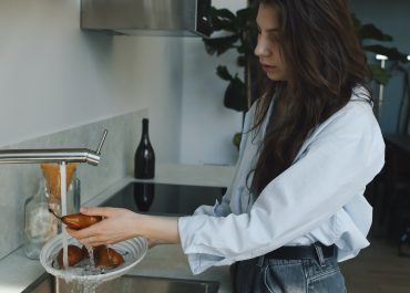 Une femme utilise l'eau du robinet chauffée par un chauffe-eau thermodynamique