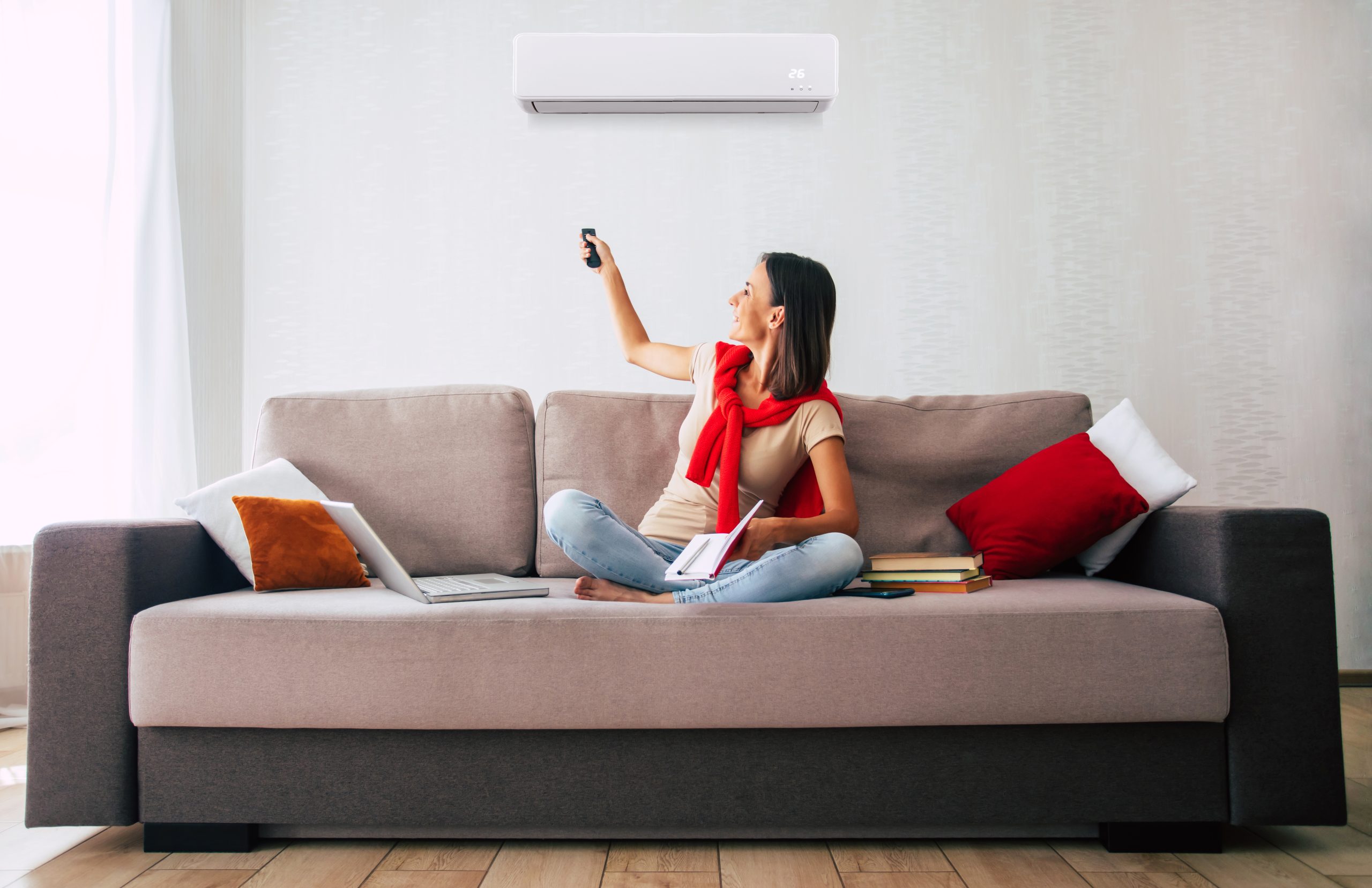 Une femme régalant sa climatisation réversible pour maitriser sa consommation énergetique